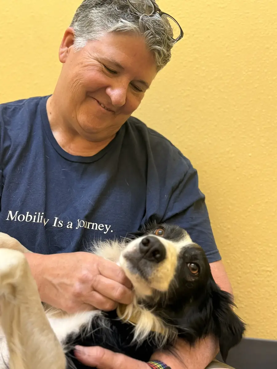 Kate holding a relaxed dog in their arms during a session at a canine therapy center.