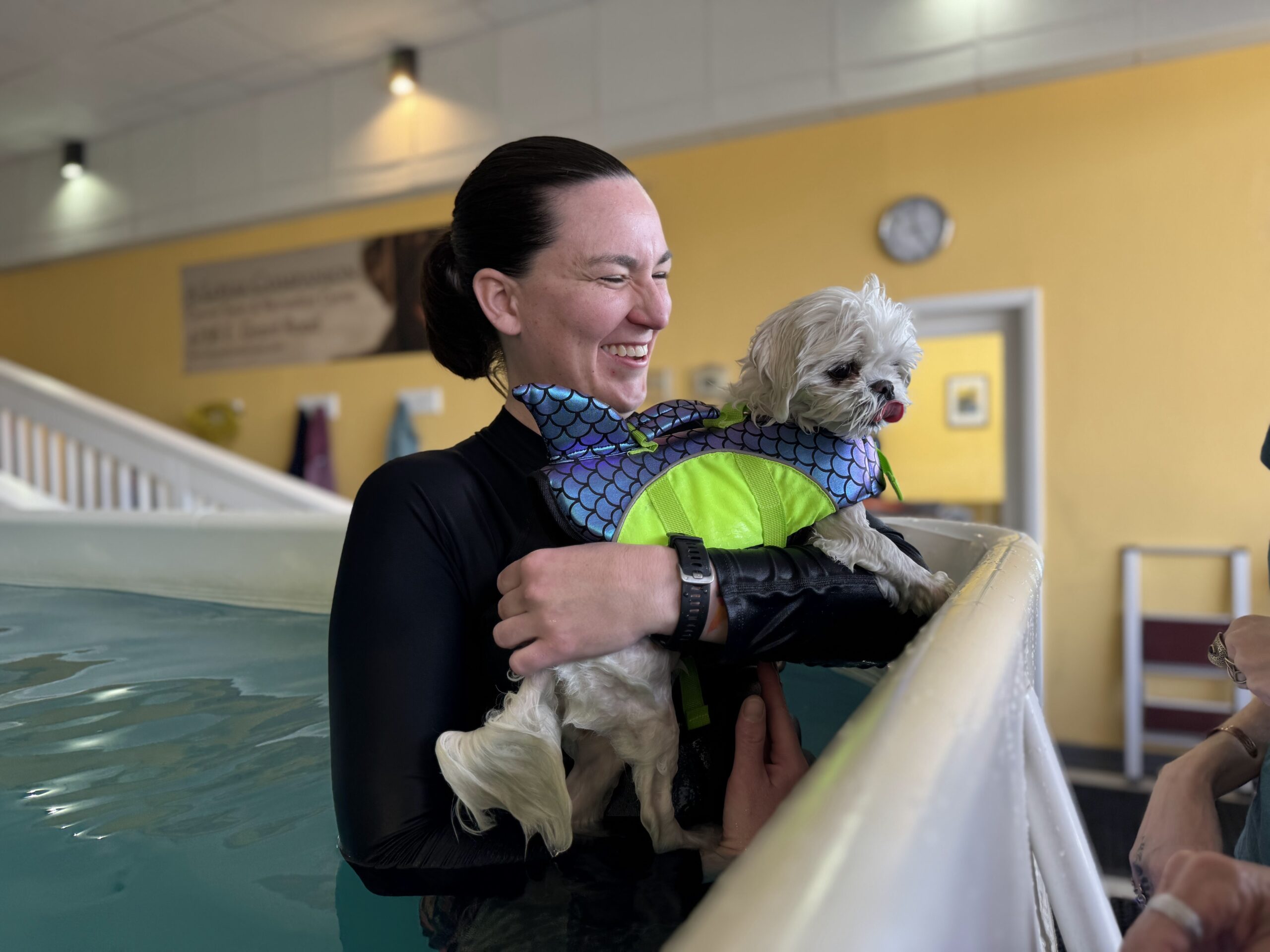 Coach and small white dog wearing a shark costume in the pool